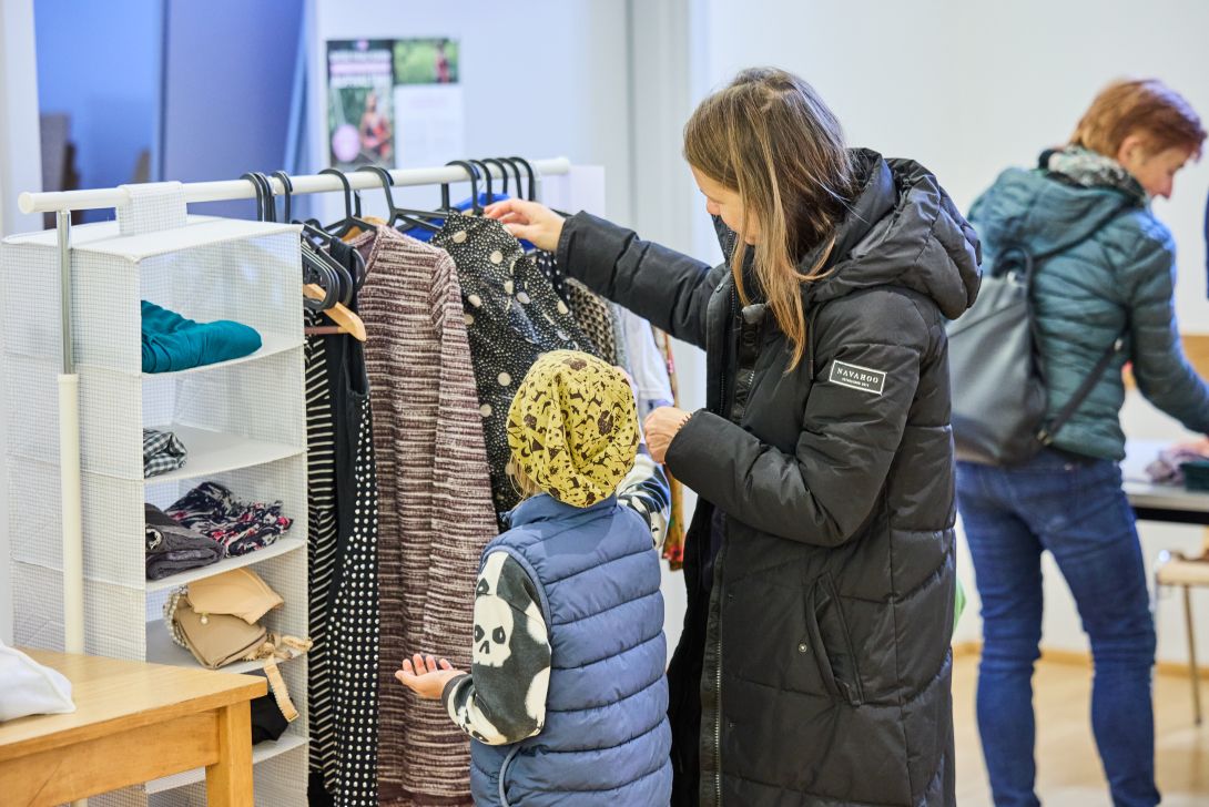 Mutter mit Kind schaut sich Kleidungsstücke bei der Tauschbar an