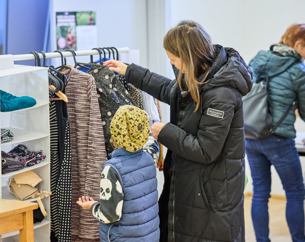 Mutter mit Kind schaut sich Kleidungsstücke bei der Tauschbar an