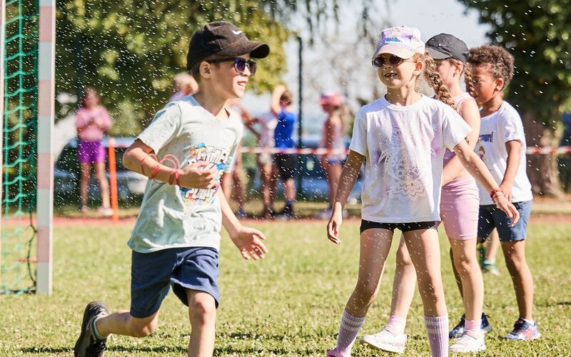 Kinder laufen beim LaufWunder unter einer Sprinkleranlage durch, um sich zu erfrischen.
