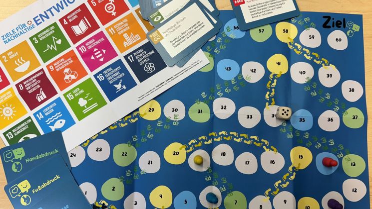 Das Spiel zur Förderung nachhaltiger Entwicklung mit einem Spielbrett, Karten und einem Würfel auf einem Tisch.