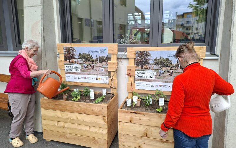 Zwei Menschen beim Gießen der Beete.