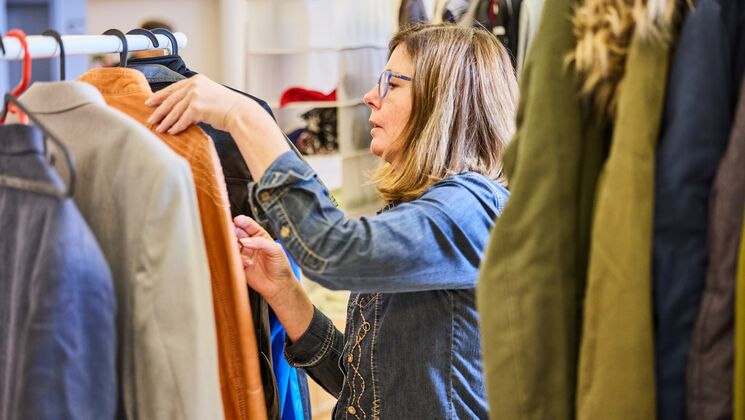 Eine Frau betrachtet sorgfältig die Auswahl an Kleidungsstücken bei einem Event.