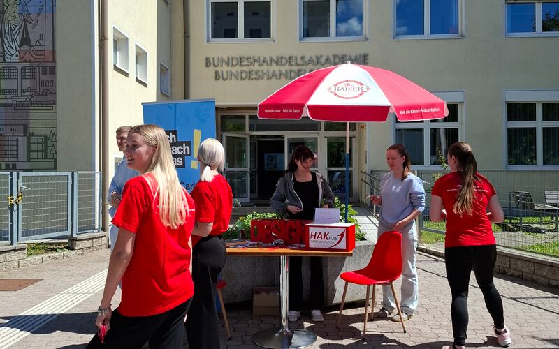 Schüler*innen stehen unter einem Schirm und reden miteinander.