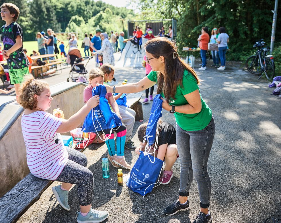 Mitarbeiterin teilt Goodiebags an Kinder aus