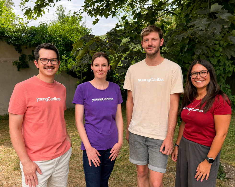 die vier Teammitglieder, zwei Männer in lachsfarbenem und cremfarbenen T-Shirt und zwei Frauen mit violettem und dunkel rotem T-Shirt, alle mit youngCaritas Schriftzug, stehen vor grünem Hintergrund